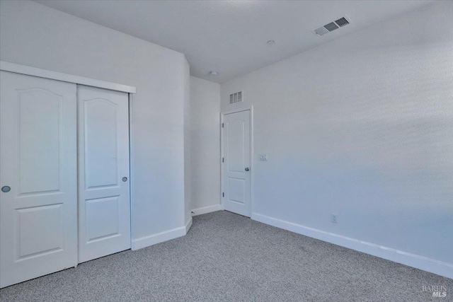 unfurnished bedroom with light colored carpet and a closet