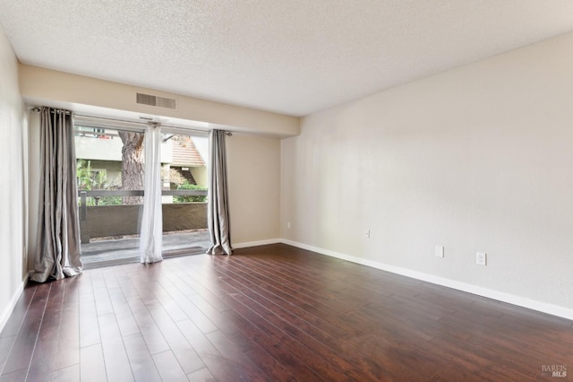 spare room featuring dark hardwood / wood-style flooring and a textured ceiling