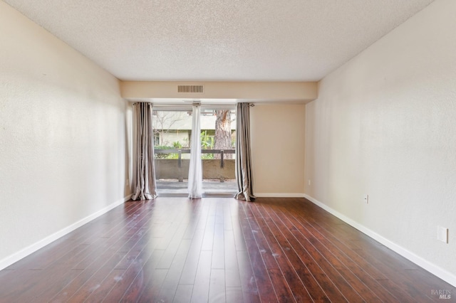 empty room featuring dark wood-type flooring and a textured ceiling