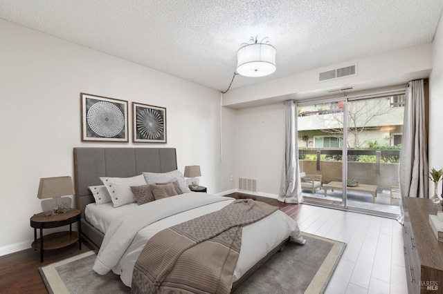 bedroom featuring access to exterior, dark wood-type flooring, and a textured ceiling