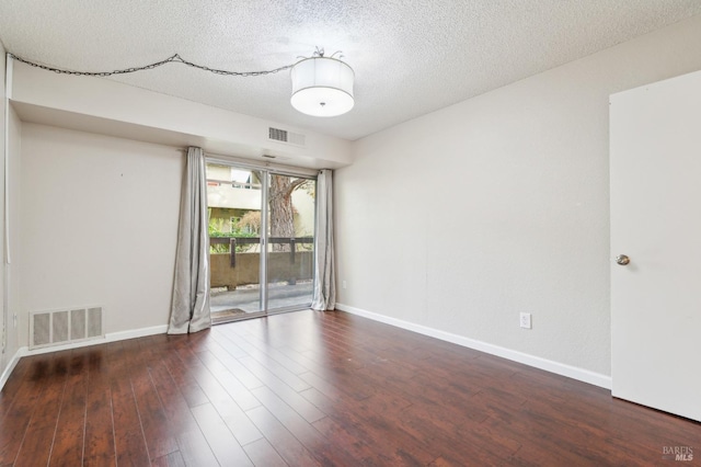 spare room featuring dark hardwood / wood-style floors and a textured ceiling