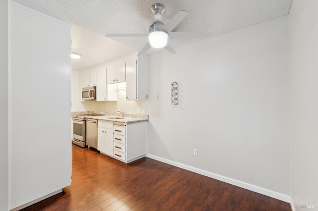 kitchen featuring ceiling fan, white cabinetry, stainless steel appliances, dark hardwood / wood-style floors, and a textured ceiling