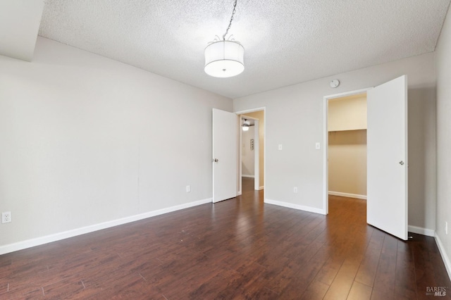 spare room with dark hardwood / wood-style floors and a textured ceiling