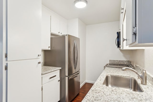 kitchen with stainless steel appliances, white cabinetry, light stone countertops, and sink