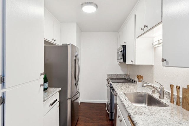 kitchen with sink, dark hardwood / wood-style floors, stainless steel appliances, light stone countertops, and white cabinets