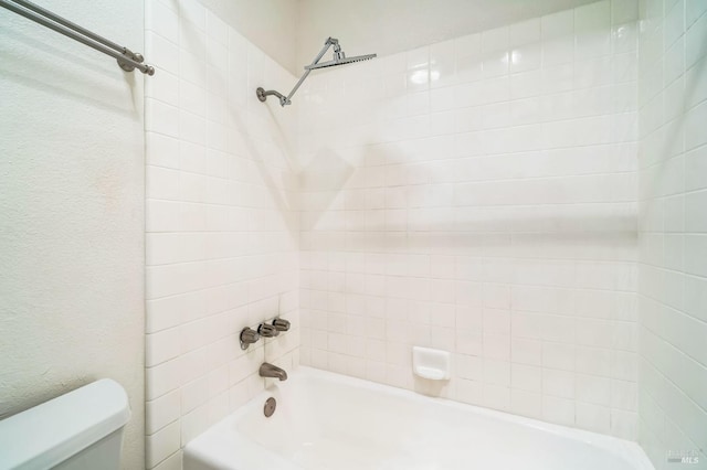 bathroom featuring tiled shower / bath combo and toilet