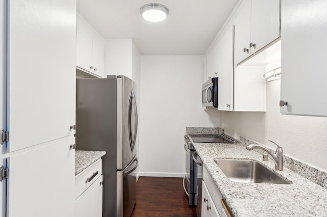 kitchen featuring appliances with stainless steel finishes, sink, white cabinets, light stone countertops, and dark wood-type flooring