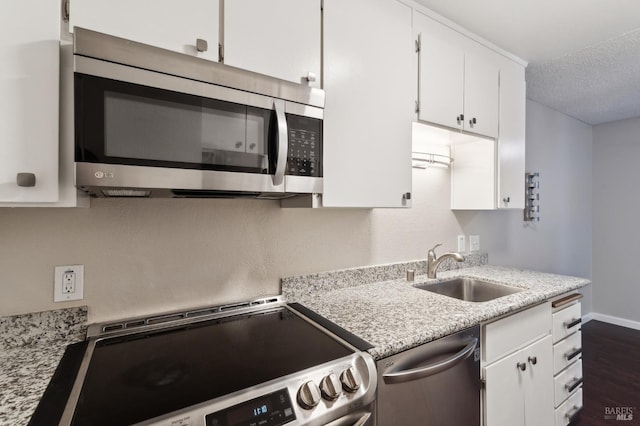 kitchen with sink, a textured ceiling, white cabinets, and appliances with stainless steel finishes