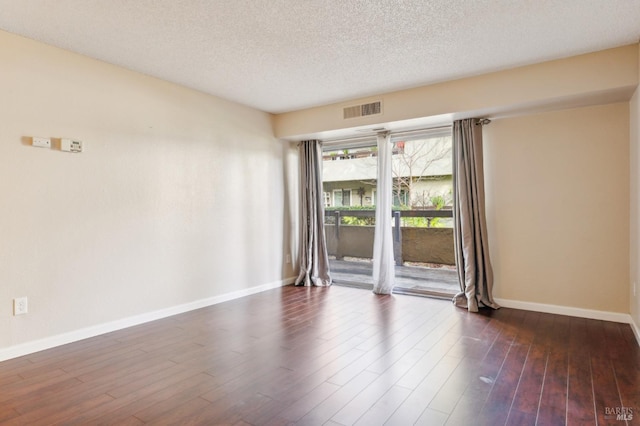 empty room with dark hardwood / wood-style floors and a textured ceiling