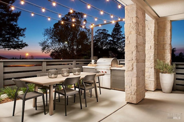 patio terrace at dusk with an outdoor kitchen and grilling area