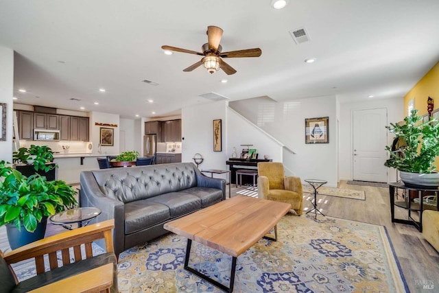 living room featuring sink, light hardwood / wood-style flooring, and ceiling fan