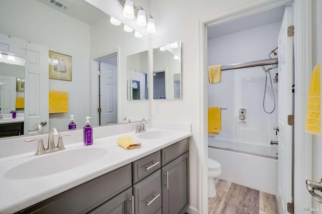 full bathroom with vanity, hardwood / wood-style floors, shower / bath combination with glass door, and toilet