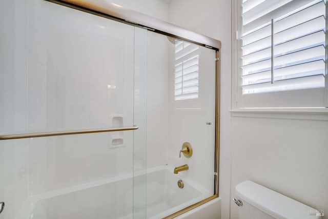 bathroom featuring bath / shower combo with glass door and toilet