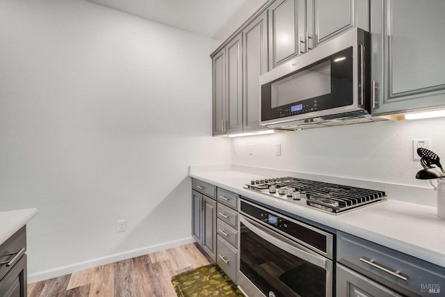 kitchen featuring stainless steel appliances, gray cabinetry, and light hardwood / wood-style flooring