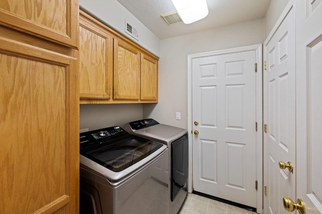 laundry area with independent washer and dryer, cabinets, and light tile patterned flooring