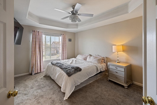 carpeted bedroom featuring a tray ceiling and ceiling fan