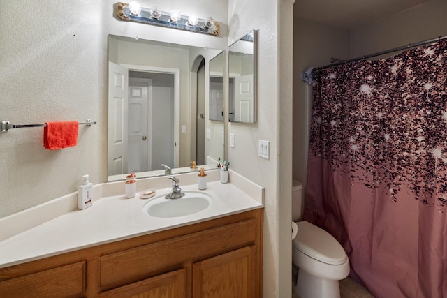 bathroom featuring vanity, curtained shower, and toilet