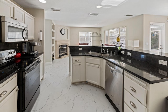 kitchen with white cabinetry, sink, dark stone counters, and appliances with stainless steel finishes