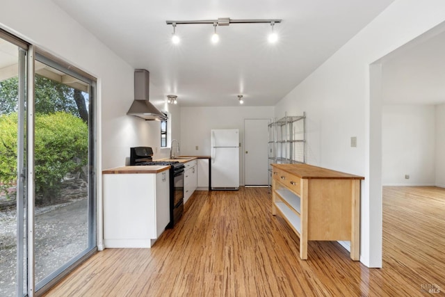 kitchen featuring extractor fan, sink, white fridge, light wood-type flooring, and black range with gas cooktop