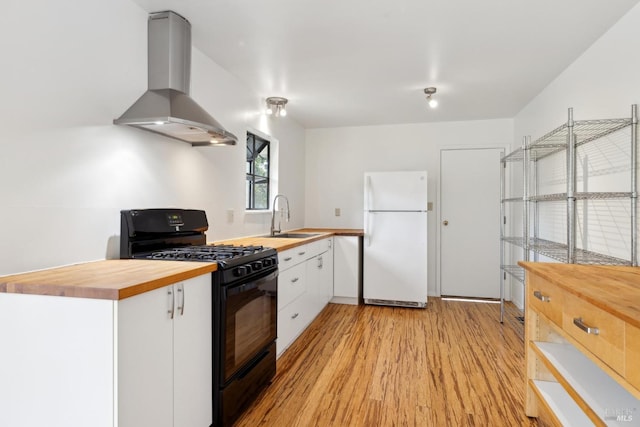 kitchen with wooden counters, black gas stove, white cabinetry, white refrigerator, and island exhaust hood