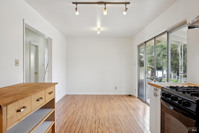 kitchen with butcher block counters, gas stove, light hardwood / wood-style flooring, light brown cabinets, and track lighting