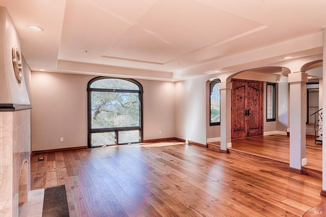 interior space with ornate columns, hardwood / wood-style flooring, and a raised ceiling