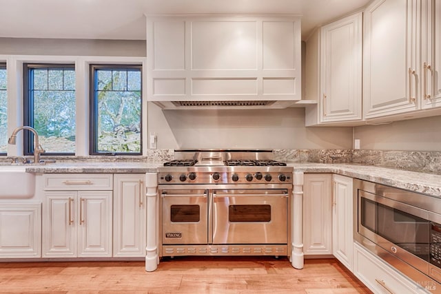 kitchen featuring sink, light stone counters, white cabinetry, light hardwood / wood-style floors, and stainless steel appliances