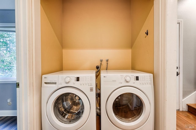 clothes washing area with a healthy amount of sunlight, washer and clothes dryer, and light hardwood / wood-style flooring