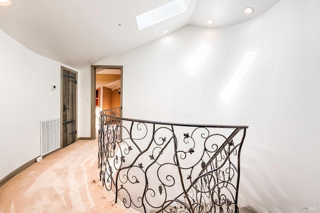 hallway featuring light colored carpet and lofted ceiling with skylight