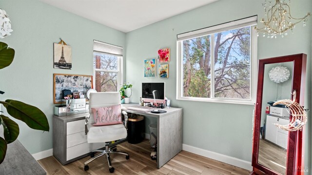 office space with an inviting chandelier, wood finished floors, and baseboards