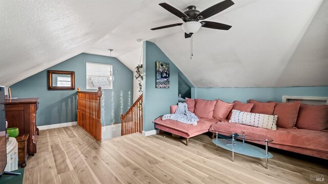 additional living space featuring lofted ceiling, a textured ceiling, baseboards, and wood finished floors