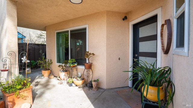 doorway to property with a patio, fence, and stucco siding