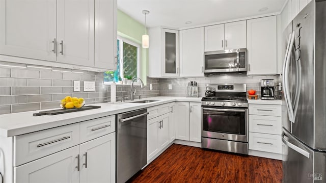 kitchen featuring dark wood finished floors, decorative backsplash, stainless steel appliances, white cabinetry, and a sink