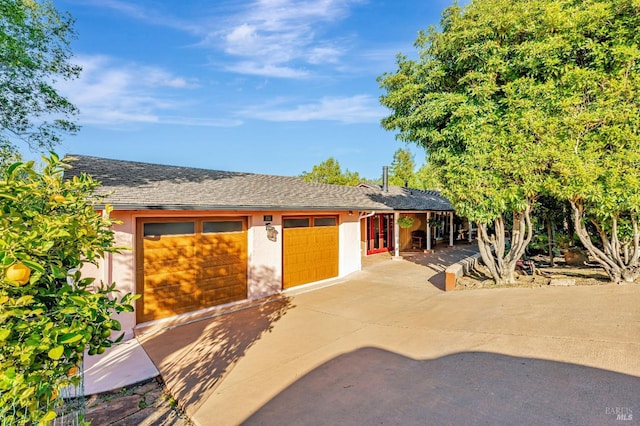 exterior space with stucco siding, concrete driveway, and roof with shingles