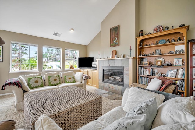 carpeted living room with high vaulted ceiling and a tile fireplace