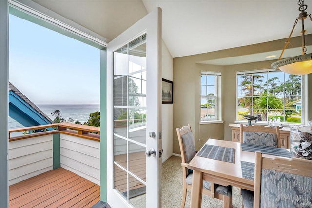 balcony with a water view and vaulted ceiling