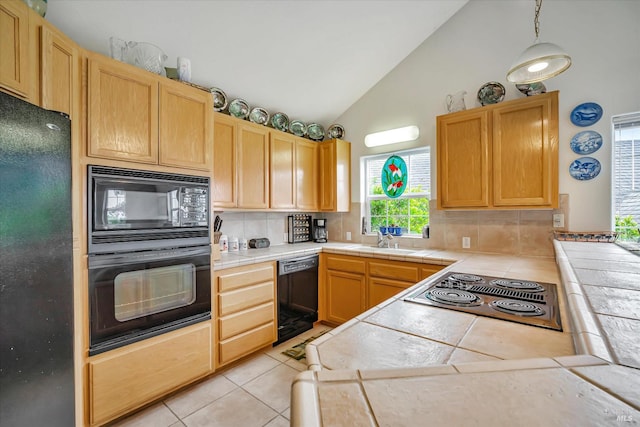 kitchen with sink, light tile patterned floors, tile counters, decorative backsplash, and black appliances