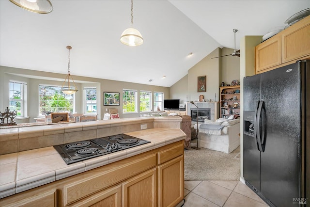 kitchen featuring tile countertops, vaulted ceiling, hanging light fixtures, light tile patterned floors, and black appliances