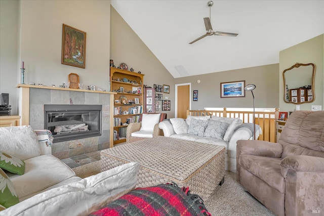 living room featuring ceiling fan, a tiled fireplace, and high vaulted ceiling