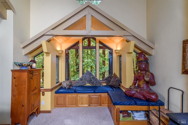 living area featuring beamed ceiling, carpet, a wealth of natural light, and high vaulted ceiling