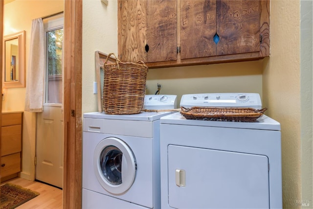 laundry room featuring cabinet space, light wood-style flooring, and washer and clothes dryer