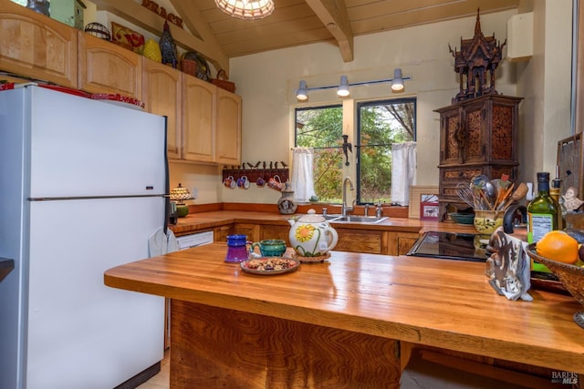 kitchen with vaulted ceiling with beams, butcher block countertops, wooden ceiling, freestanding refrigerator, and a sink