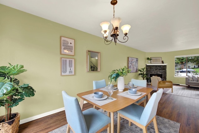 dining room featuring dark hardwood / wood-style floors, a fireplace, and a notable chandelier