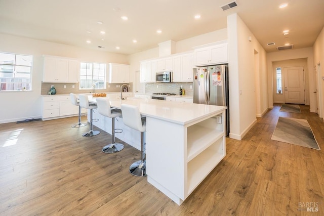 kitchen featuring stainless steel appliances, light countertops, white cabinetry, and a large island