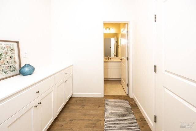 interior space with dark wood-type flooring, a sink, and baseboards