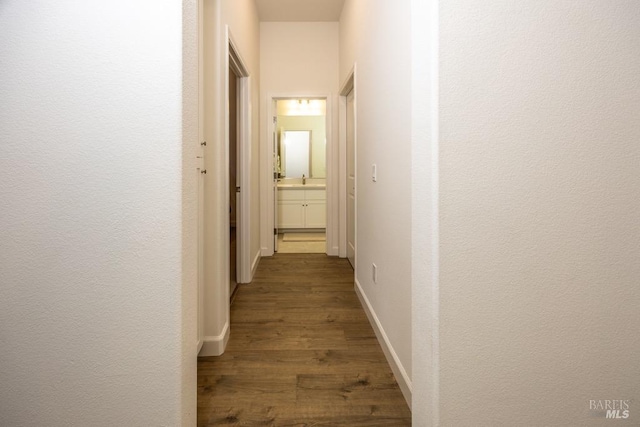 corridor with dark wood-type flooring and baseboards