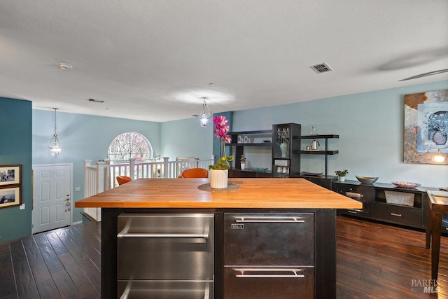 kitchen featuring hanging light fixtures, a kitchen island, wooden counters, and dark hardwood / wood-style flooring