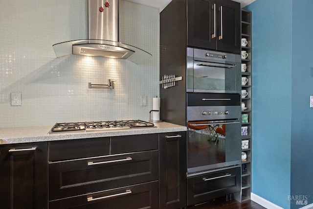 kitchen featuring stainless steel gas cooktop, decorative backsplash, and wall chimney exhaust hood