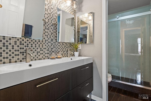 bathroom with backsplash, hardwood / wood-style flooring, vanity, walk in shower, and toilet