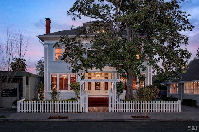 view of front of house with a fenced front yard and a chimney